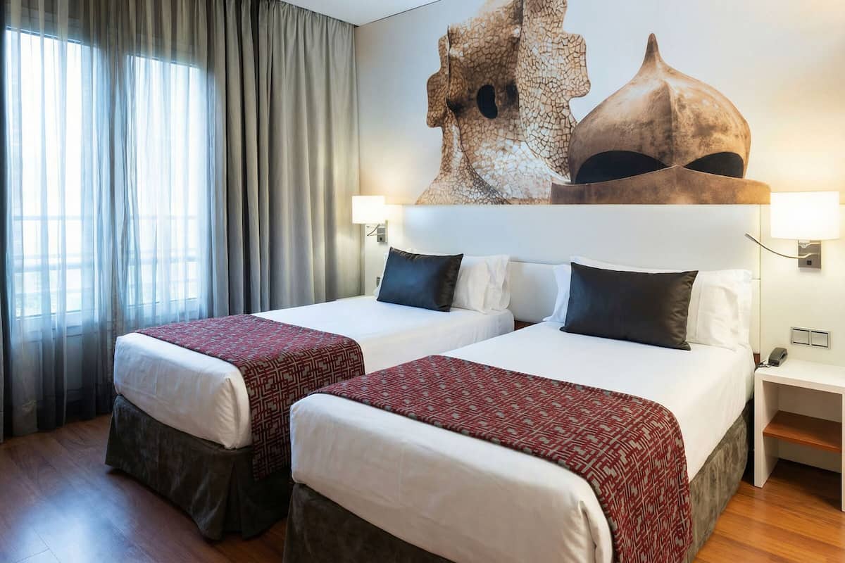 A hotel room with two beds, a large abstract artwork on the wall, a nightstand, and a window with curtains.
