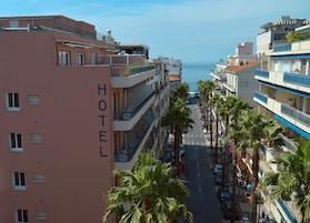 A hotel with multiple floors, balconies, and a view of the sea.