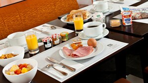 A breakfast table set with various breakfast items, including eggs, toast, fruit, and juice. - Best Western Astoria (Antibes)