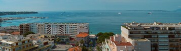 A coastal cityscape with modern buildings, a marina with boats, and a clear view of the sea.
