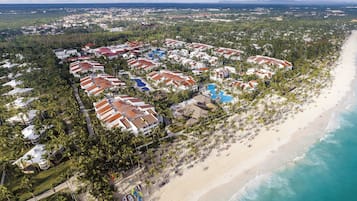 Luchtbeeld van een resort met meerdere gebouwen, een strand en een zwembad.