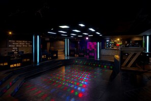 A dimly lit bar area with a pool table and neon lights.