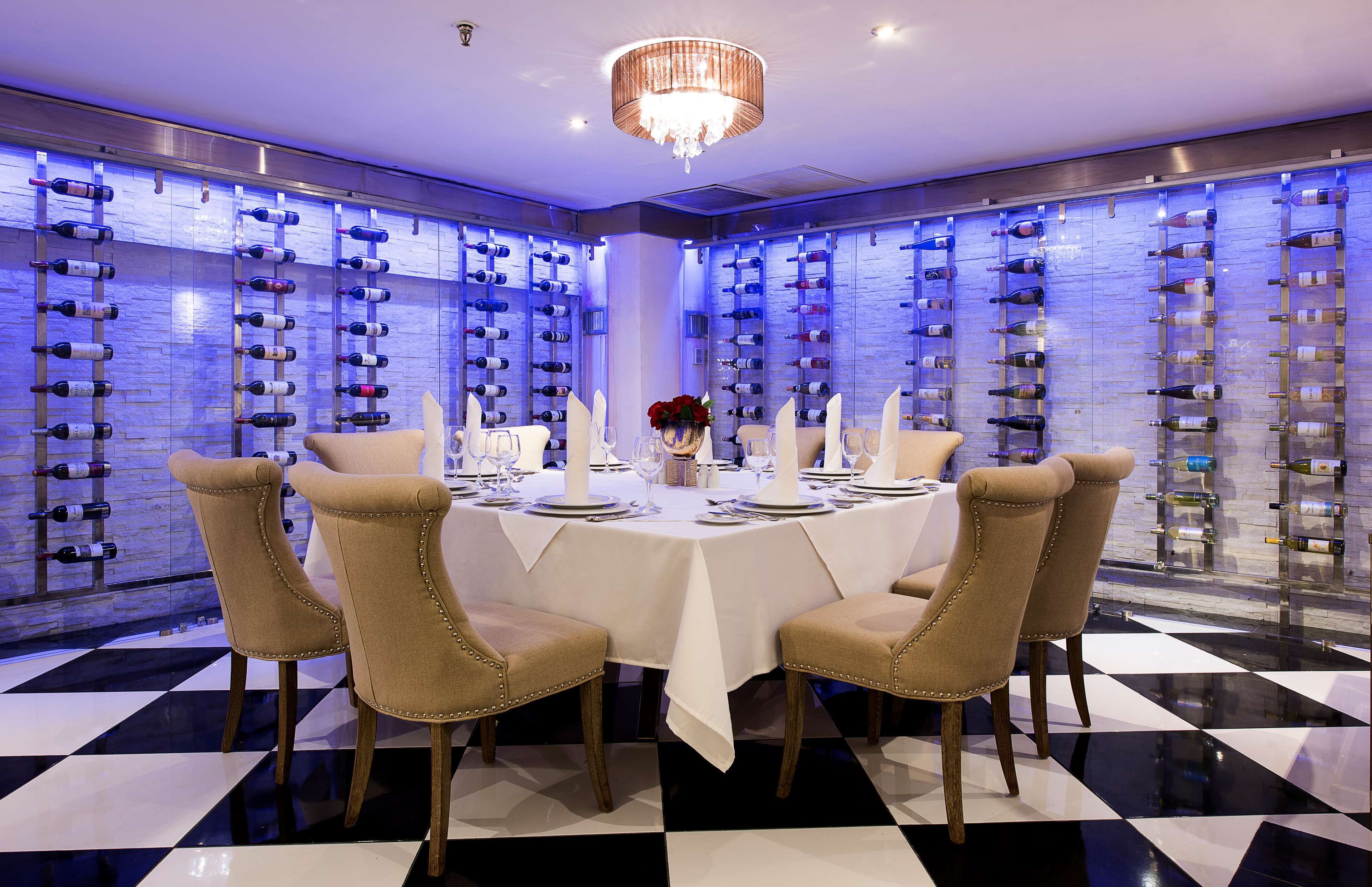 A dining area with a checkered floor, a chandelier, and wine racks on the walls.