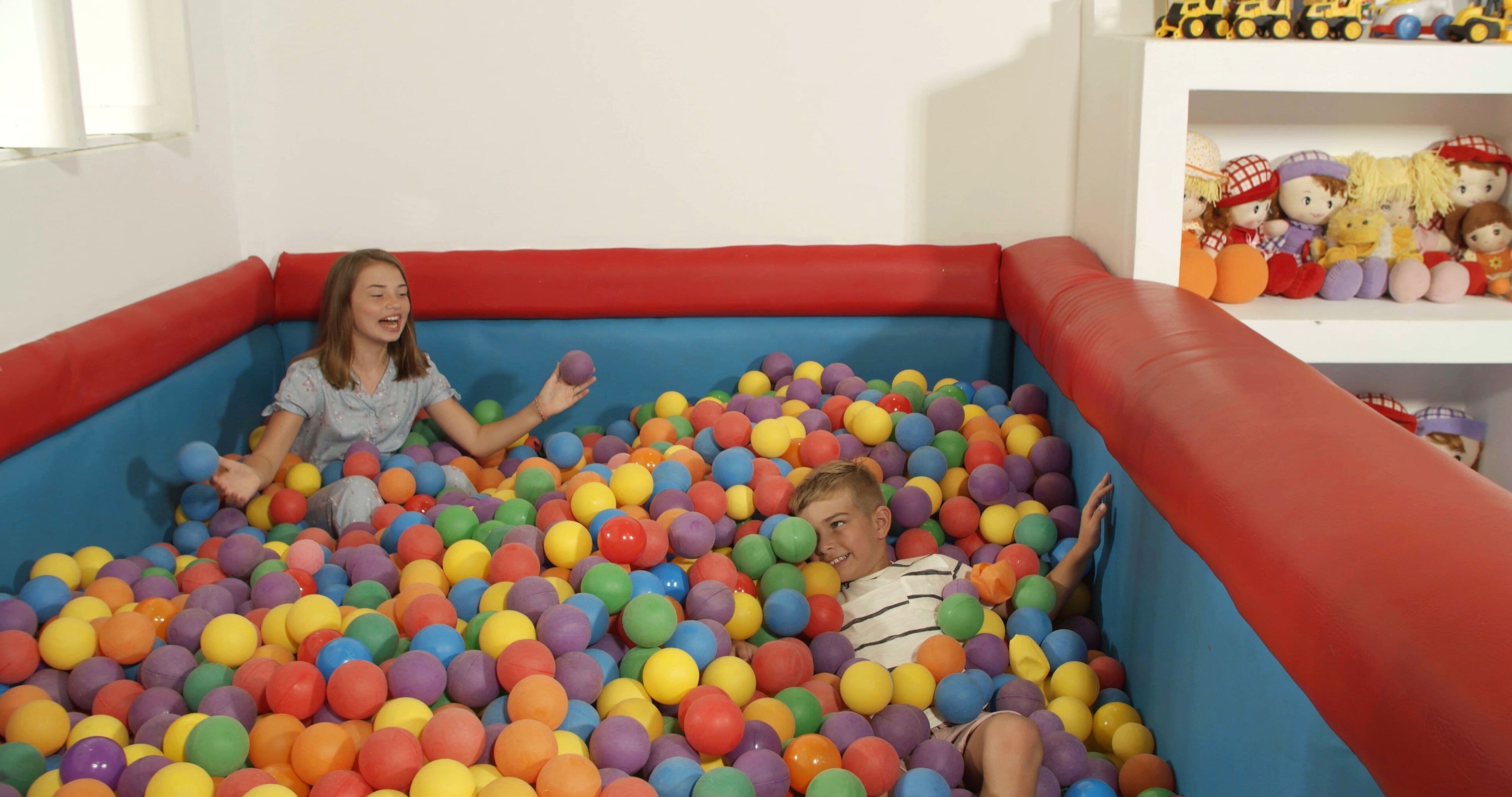 Un colorido chapuzón con pelotas inflables donde juegan dos niños.