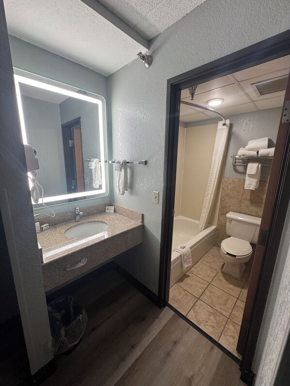 A bathroom with a sink, mirror, and shower.
