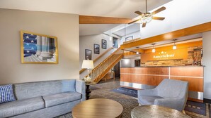 A hotel lobby with a reception desk, a staircase, a sofa, and a coffee table. - AmericInn by Wyndham Albert Lea (Albert Lea)