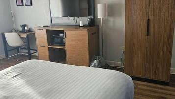 Ein Hotelzimmer mit Bett, Schreibtisch mit Stuhl, Fernseher, Kleiderschrank und Lampe.