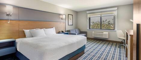 Habitación de hotel con una cama grande, un escritorio, una silla, un ventanal y un radiador.