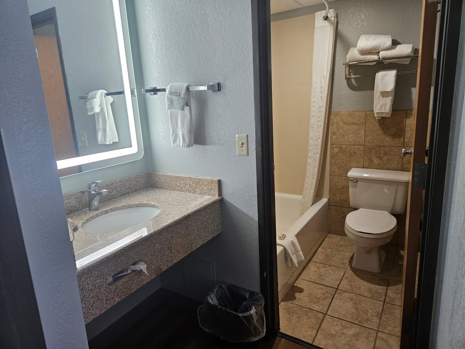 A bathroom with a sink, mirror, towel rack, shower, and toilet.
