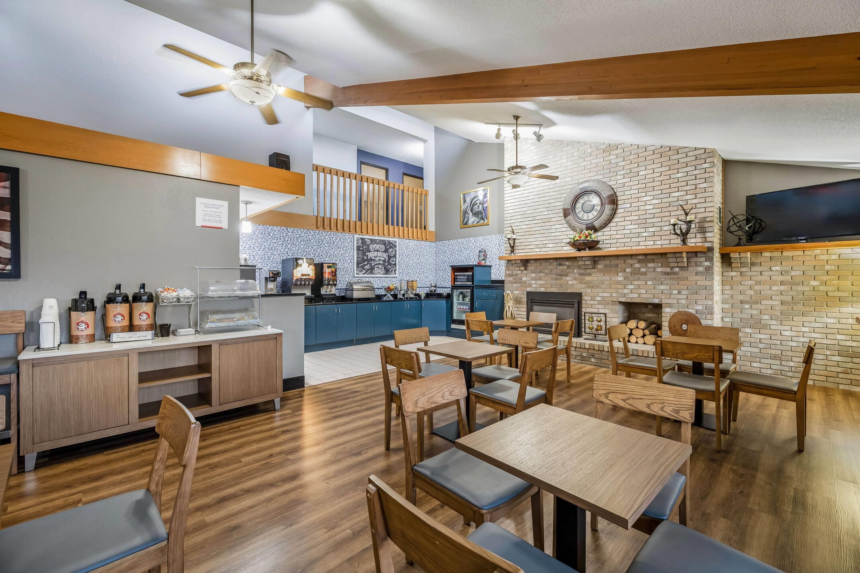 A restaurant with a brick wall, wooden ceiling beams, and a fireplace.