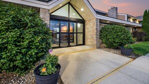 A modern building with a prominent entrance, large windows, and a landscaped garden. - AmericInn by Wyndham Albert Lea (Albert Lea)