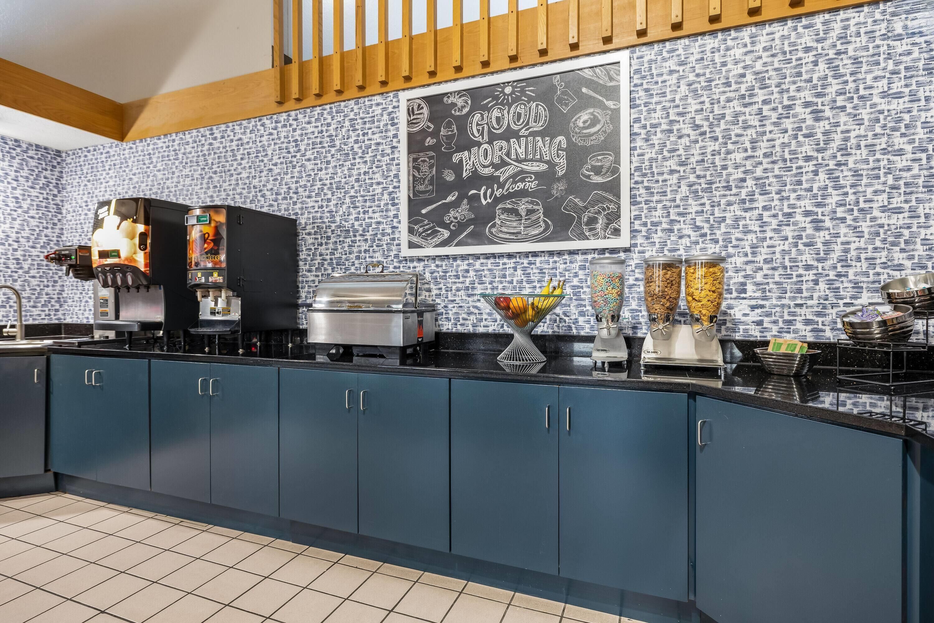 A kitchen with a coffee machine, a chalkboard with food illustrations, and various food containers.
