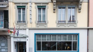 En hotels facade med et stort vindue, en glasindgang og en balkon med gelændere.
