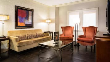 A living room with a sofa, two armchairs, a coffee table, and a painting on the wall.