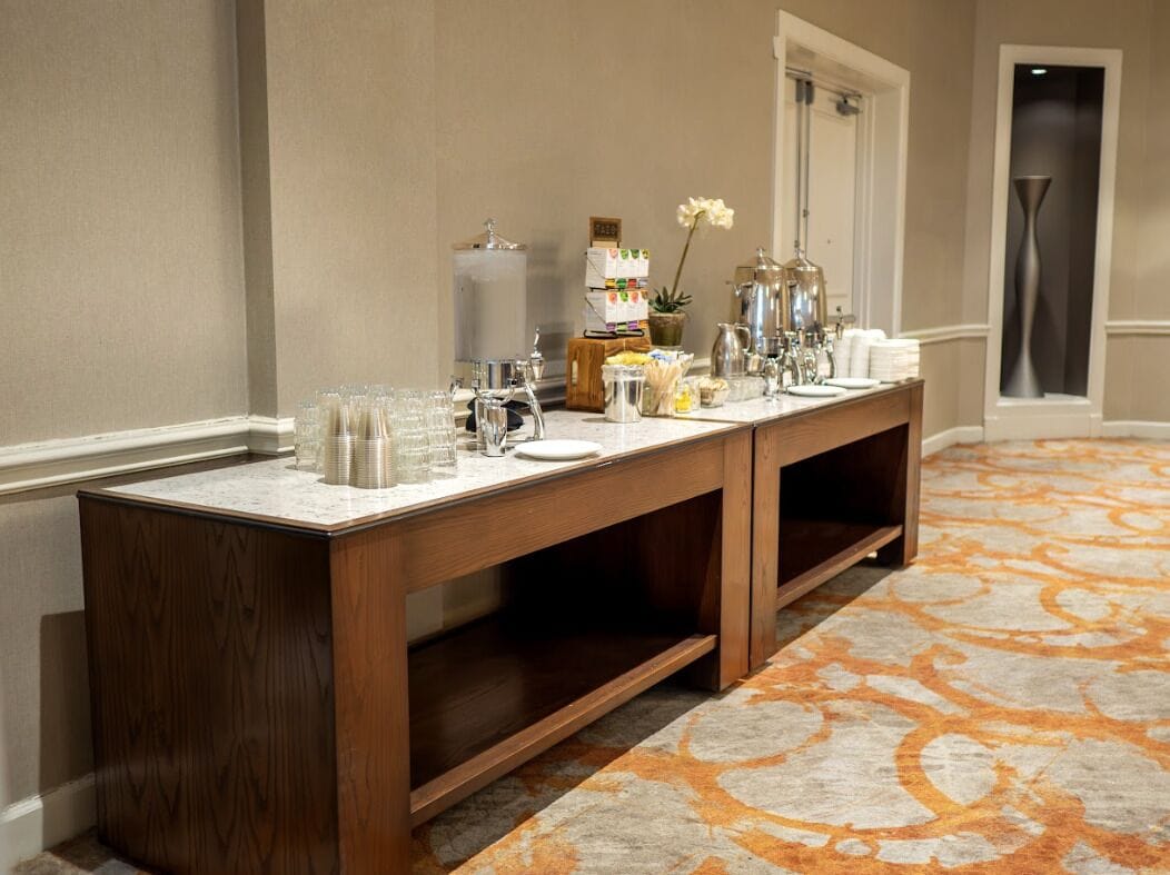 A hotel reception area with a long wooden counter, glassware, and a coffee station.