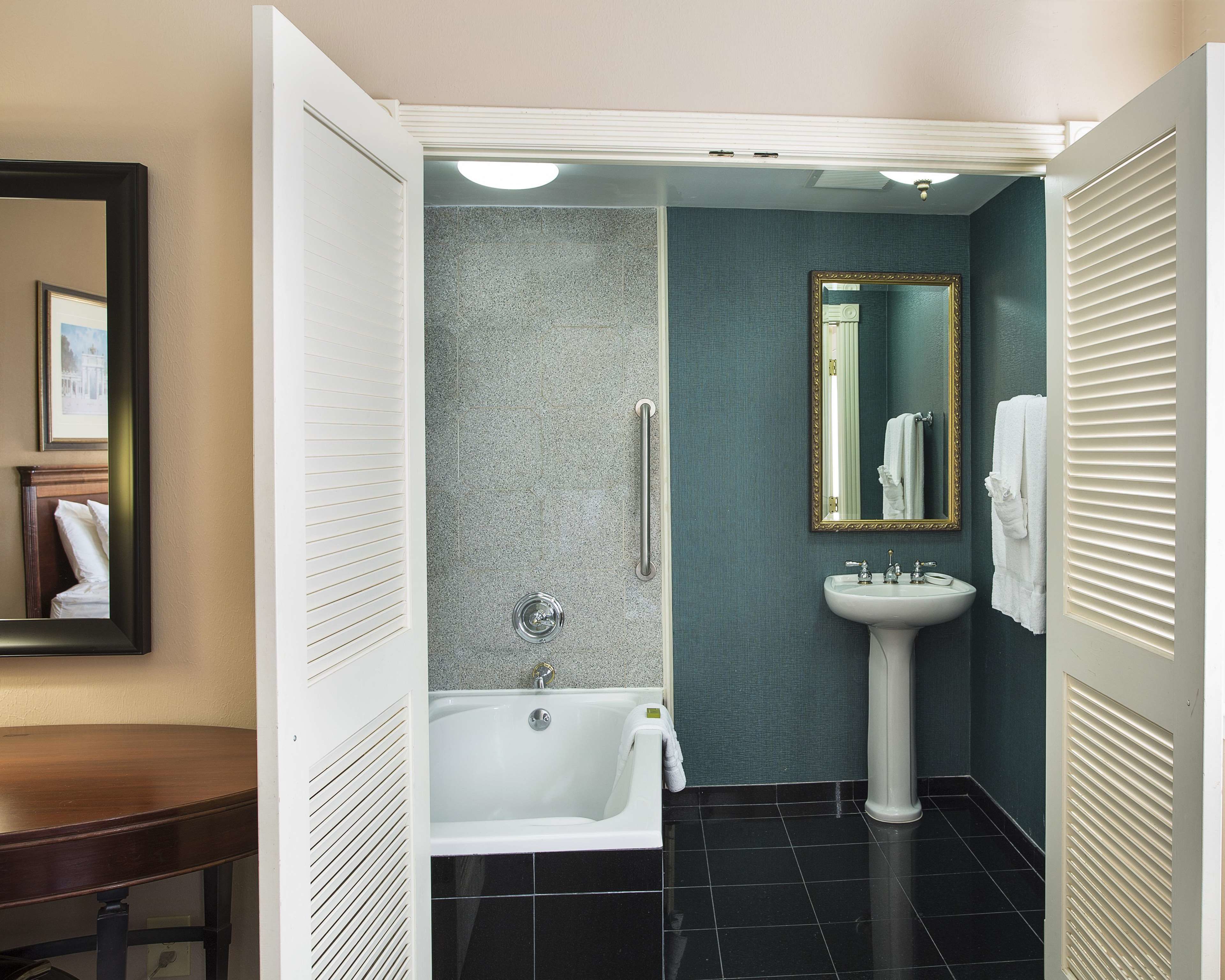 A bathroom with a bathtub, a sink, and a mirror.