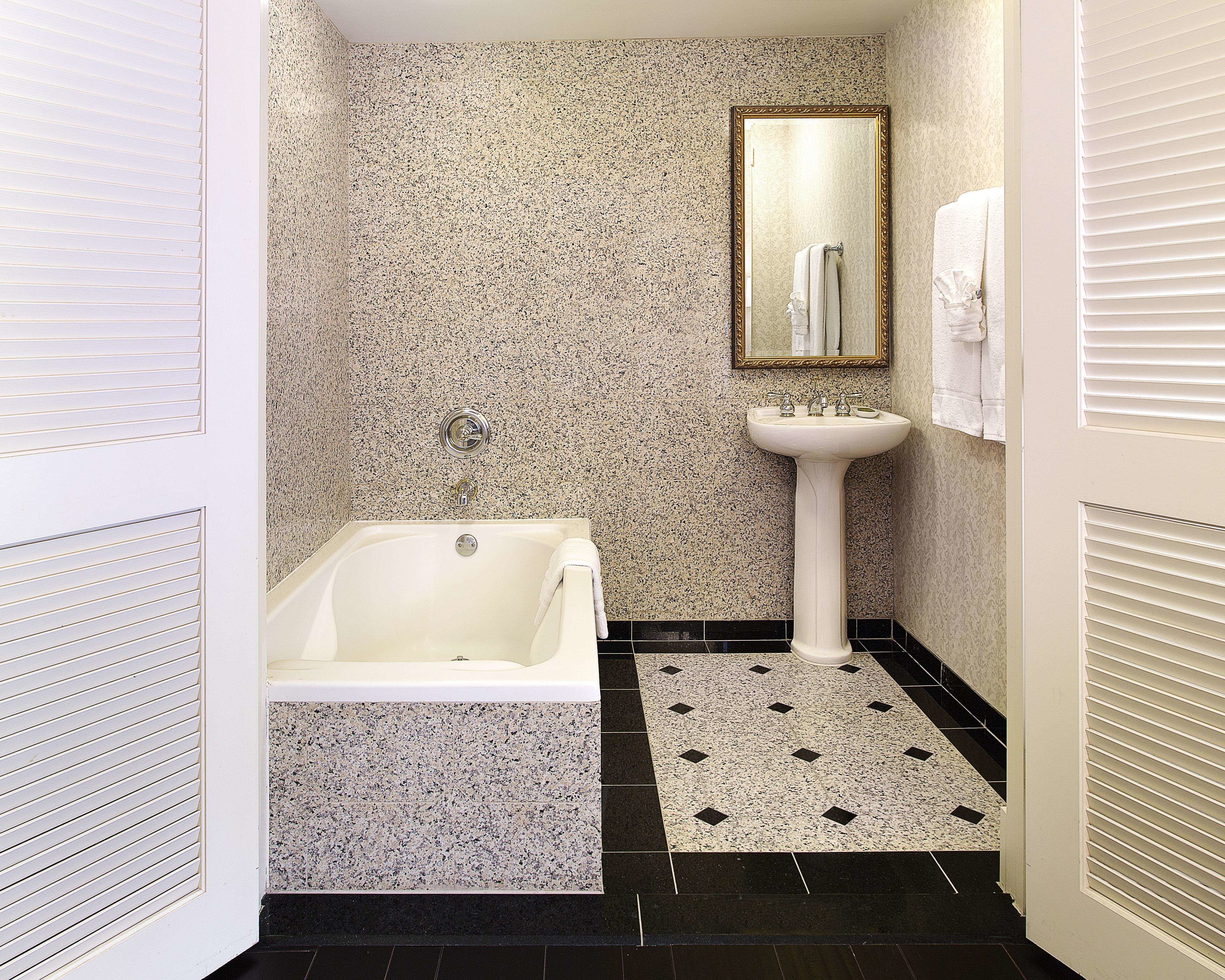 A bathroom with a bathtub, a sink, and a mirror.