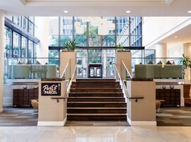 A hotel lobby with a staircase, large windows, and a reception desk.