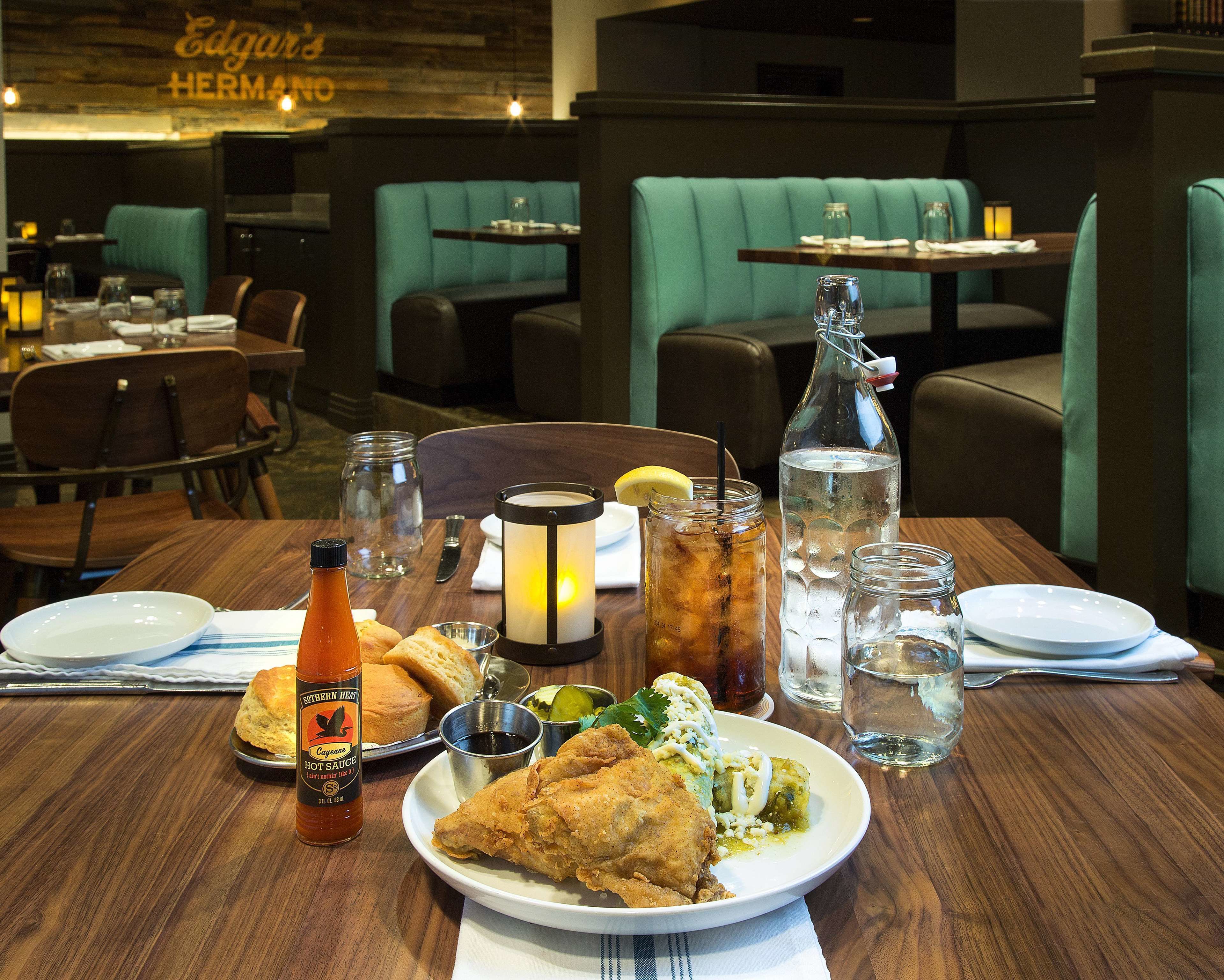 Une salle de restaurant avec des tables dressées pour le service, comprenant des assiettes, des boissons et des condiments.