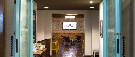 Entrada de un hotel con un letrero que dice 'Edgar's Hermano' y 'The Whitehall' en una pantalla.