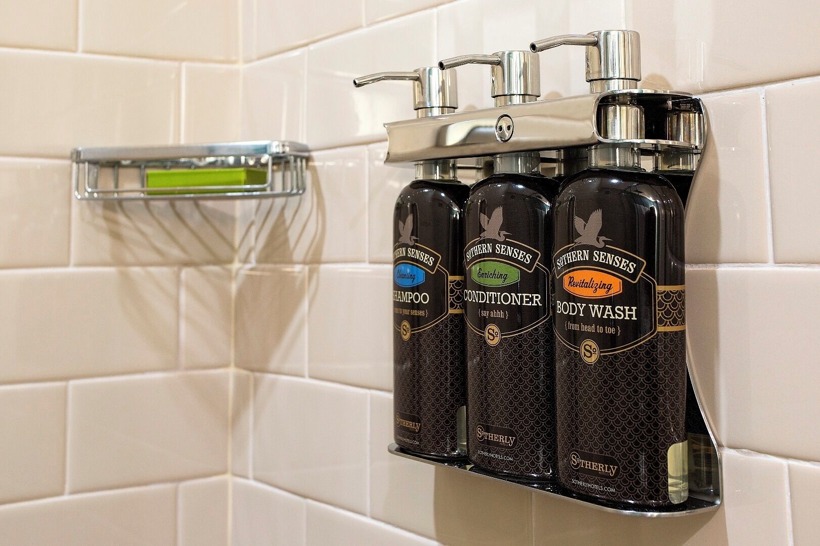 A bathroom with a chrome faucet and three bottles of Southern Senses body wash on a shelf.