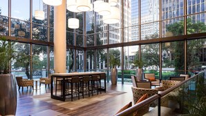 Um espaço amplo e interno com bar, assentos e grandes janelas que oferecem vista para a paisagem urbana.