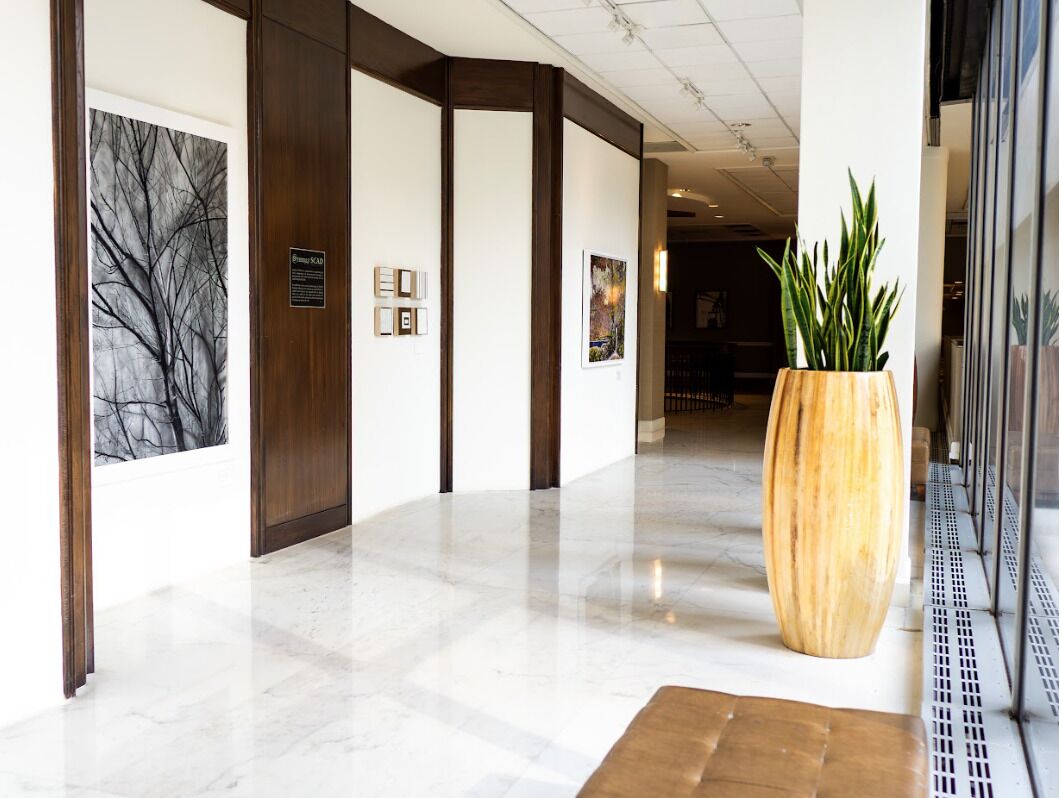 A hotel lobby with a marble floor, wooden paneling, and artwork on the walls.