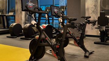 A Peloton exercise bike in a gym with a large window in the background.