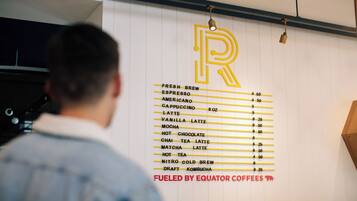 A menu board with coffee and drink options, a large 'R' logo, and a sign stating 'FUELED BY EQUATOR COFFEEES'.