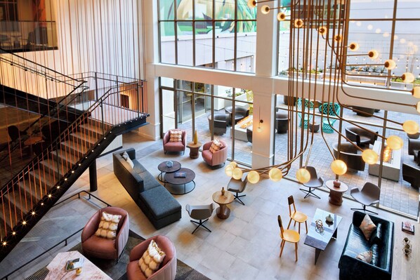 Un espace intérieur spacieux, doté d’un escalier moderne, de divers coins salon et de grandes fenêtres qui laissent entrer la lumière naturelle.