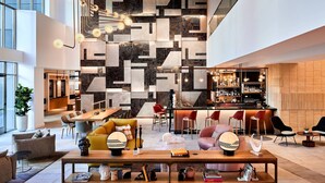 A spacious lobby with a modern bar area, seating arrangements, and a geometric wall design. -  The Clancy, Autograph Collection by Marriott (San Francisco)