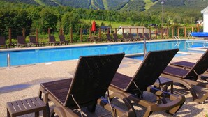 A pool area with lounge chairs and a view of a mountainous landscape. - Killington Grand Hotel (Killington)
