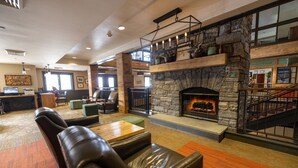 A spacious lobby with leather seating, a stone fireplace, and a staircase leading to an upper level. - Killington Grand Hotel (Killington)