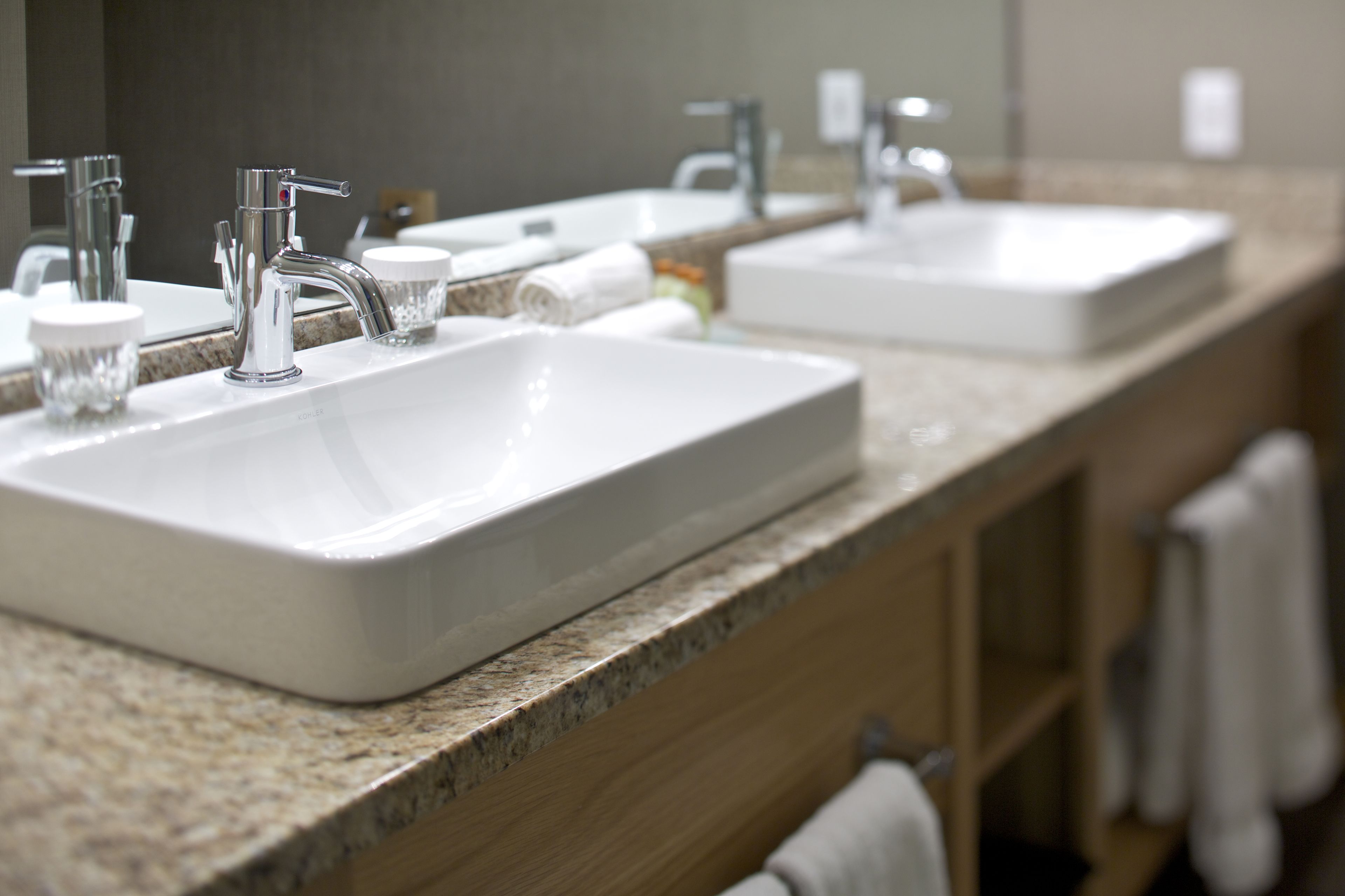 A bathroom with two sinks, a mirror, and a towel rack.