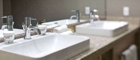 A bathroom with two sinks, a mirror, and a towel rack.