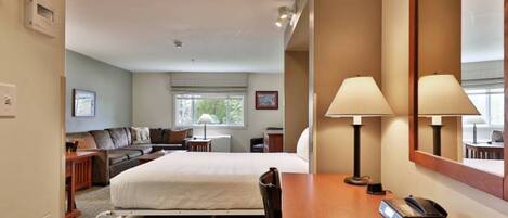 A hotel room with a bed, bedside table, lamp, phone, and a large mirror.
