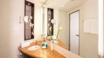 Un baño moderno con encimera de mármol, lavamanos, un espejo grande y una cabina de ducha de vidrio.