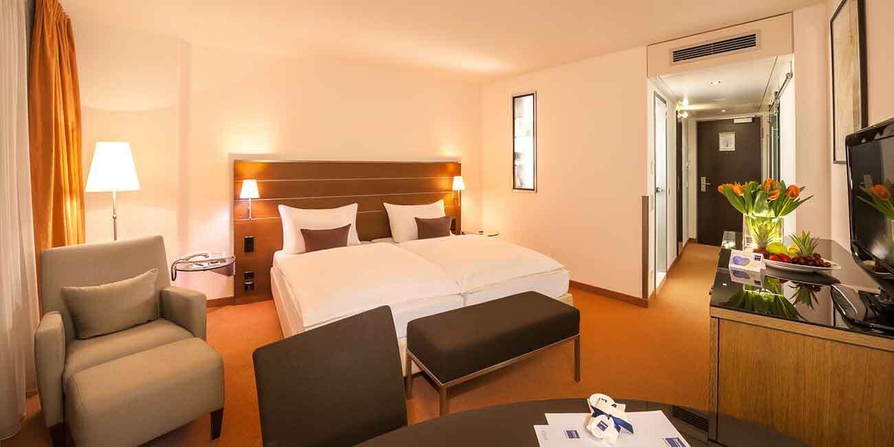 Een hotelkamer met een bed, een bureau, een stoel, een televisie en een lamp.