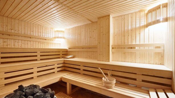 A wooden sauna with benches and a stone basin.