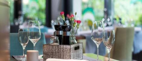 Una mesa de comedor con copas de vino, una vela y una caja decorativa con flores.