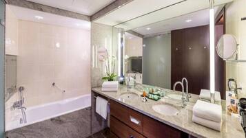 Un baño moderno con bañera, dos lavamanos, un espejo grande y un mueble de tocador con cajones.