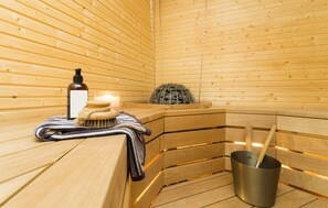 Una sauna con panche in legno, una bottiglia, una spazzola e un secchio.
