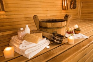 Una sauna in legno con asciugamani, candele e un catino di legno.