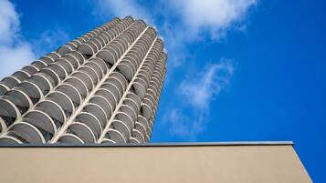 A tall building with a distinctive circular pattern of balconies against a clear blue sky.