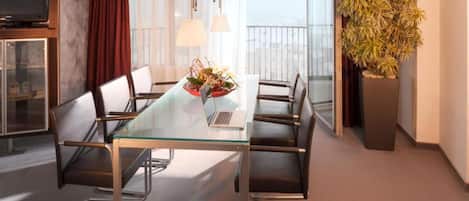 Un comedor moderno con una mesa de vidrio, sillas de metal, una computadora portátil y una planta decorativa.