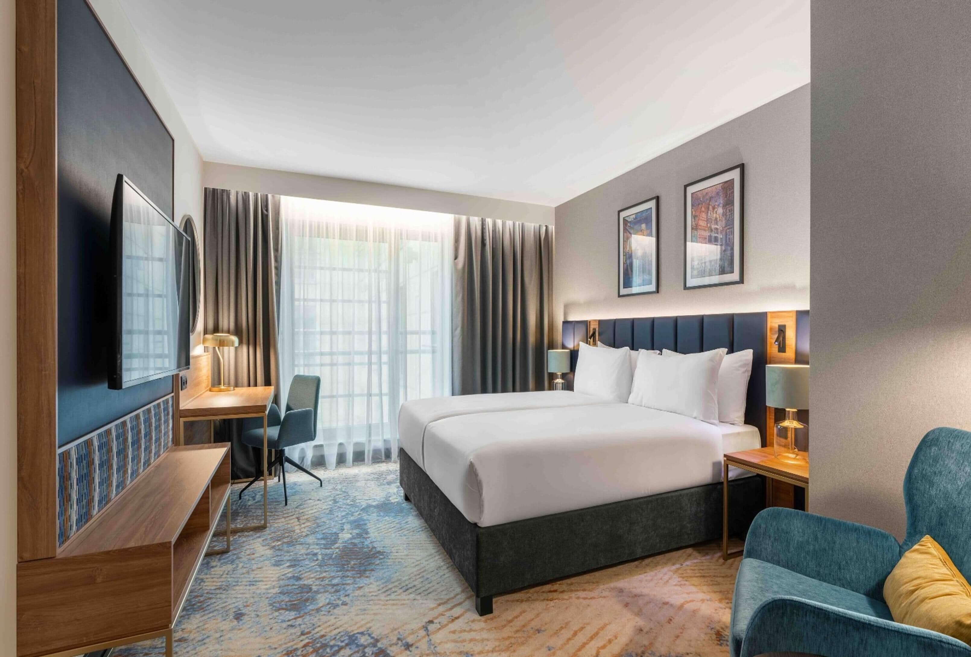 Une chambre d’hôtel avec un grand lit, un bureau avec une chaise, une télévision et un canapé.