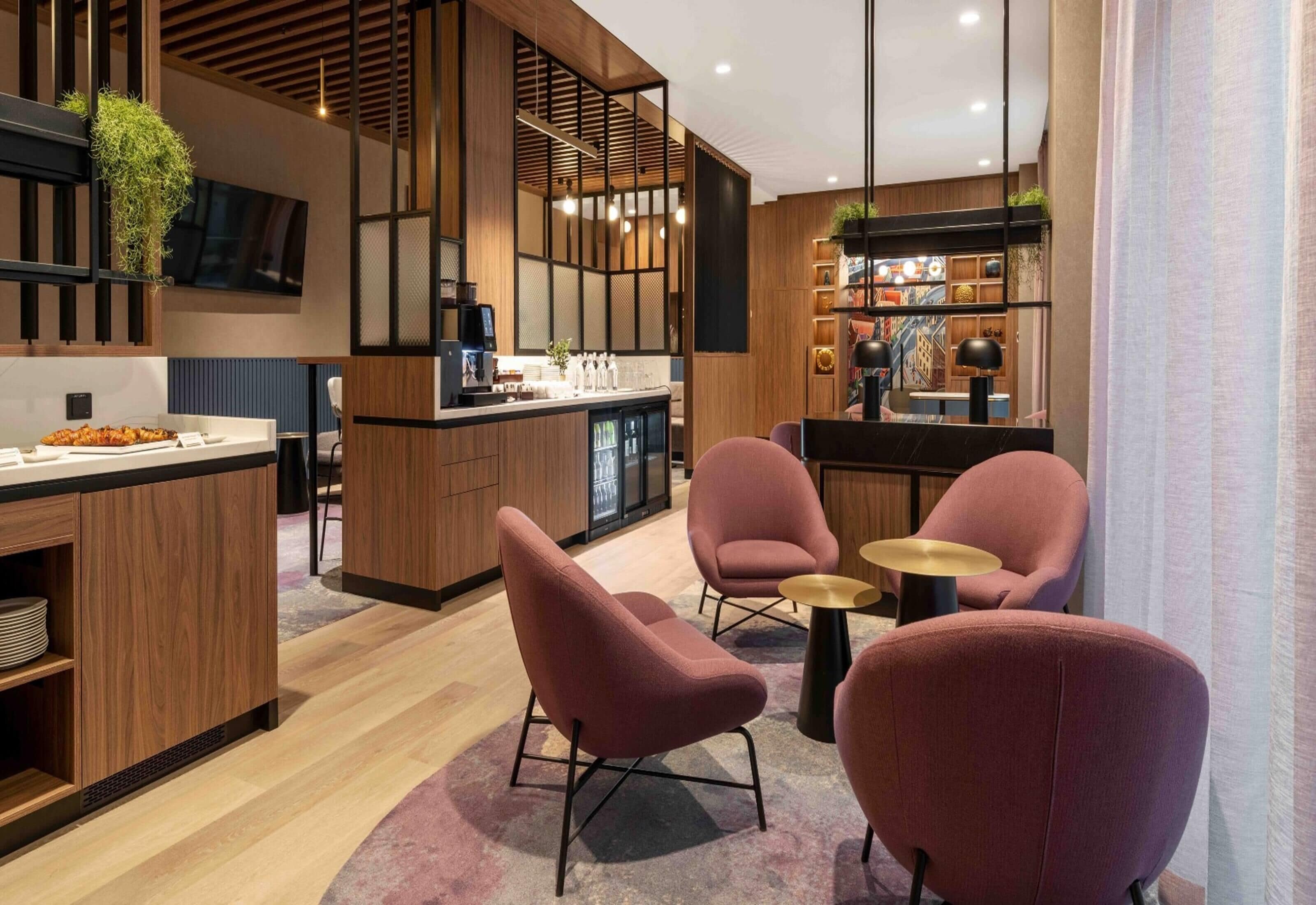 A modern kitchen with wooden accents, a bar area, and seating with round tables.