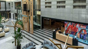 A modern lobby with a reception desk, seating area, and a staircase leading to upper floors. - Wyndham Wroclaw Old Town (Wroclaw)