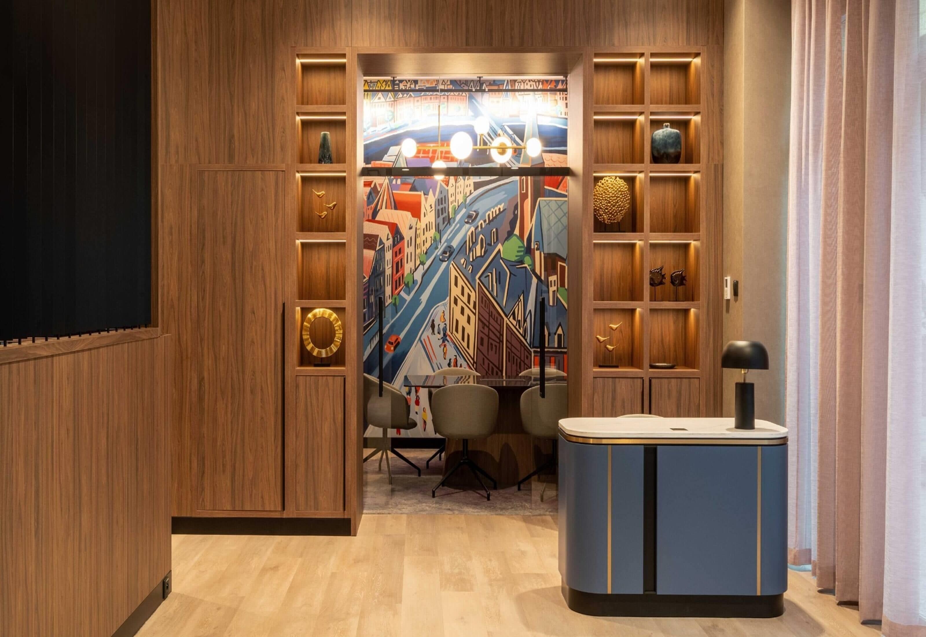 A modern room with a wooden panel wall, a colorful mural, a desk with a lamp, and a chair.