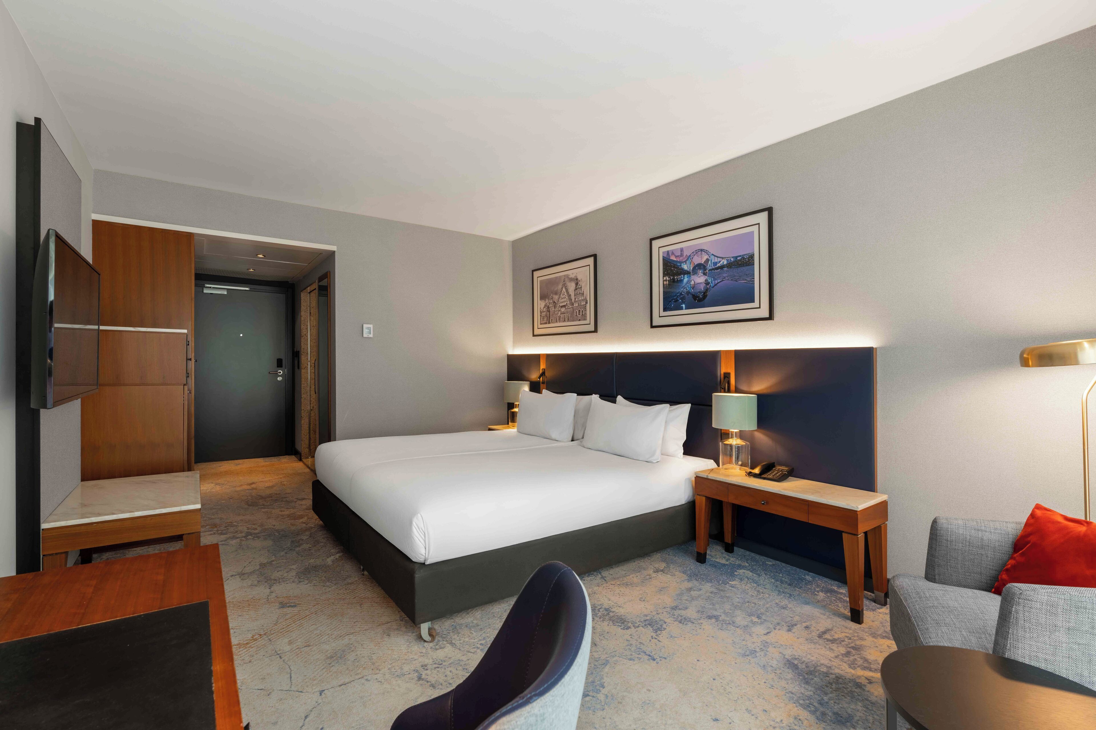 Una habitación de hotel moderna con una cama grande, un escritorio, una silla y un televisor.